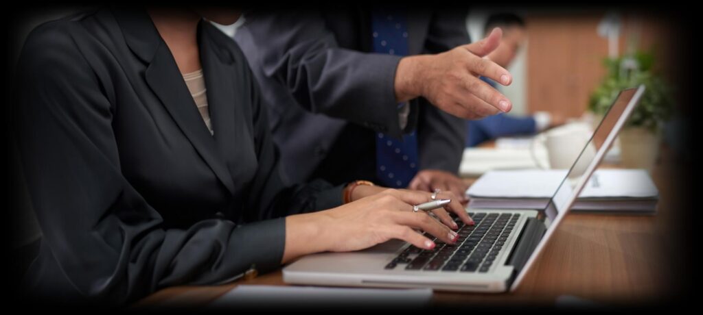 Two employees discussing things while one types in laptop