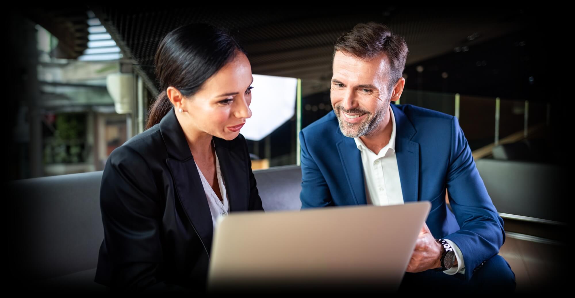 businesswoman and businessman talking while looking at a laptop